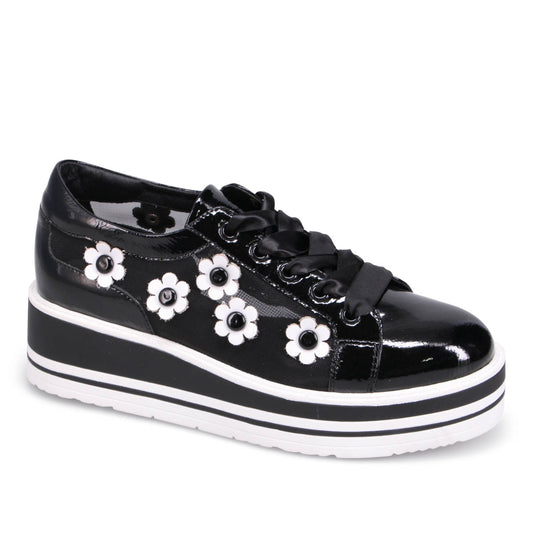 Black patent leather sneaker with white flower details and a striped platform sole.