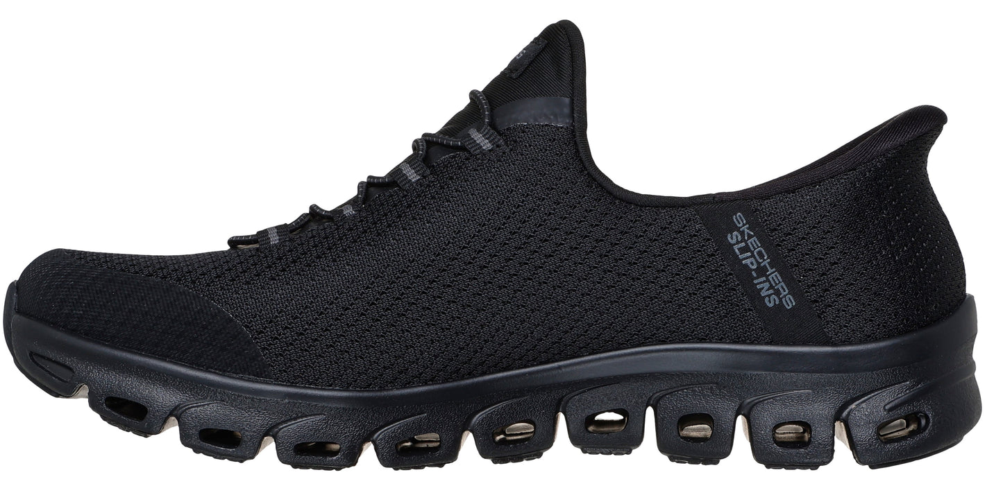 A black slip-on shoe featuring a knit upper, a decorative lace-up design, and a sculpted sole with multiple cutouts.