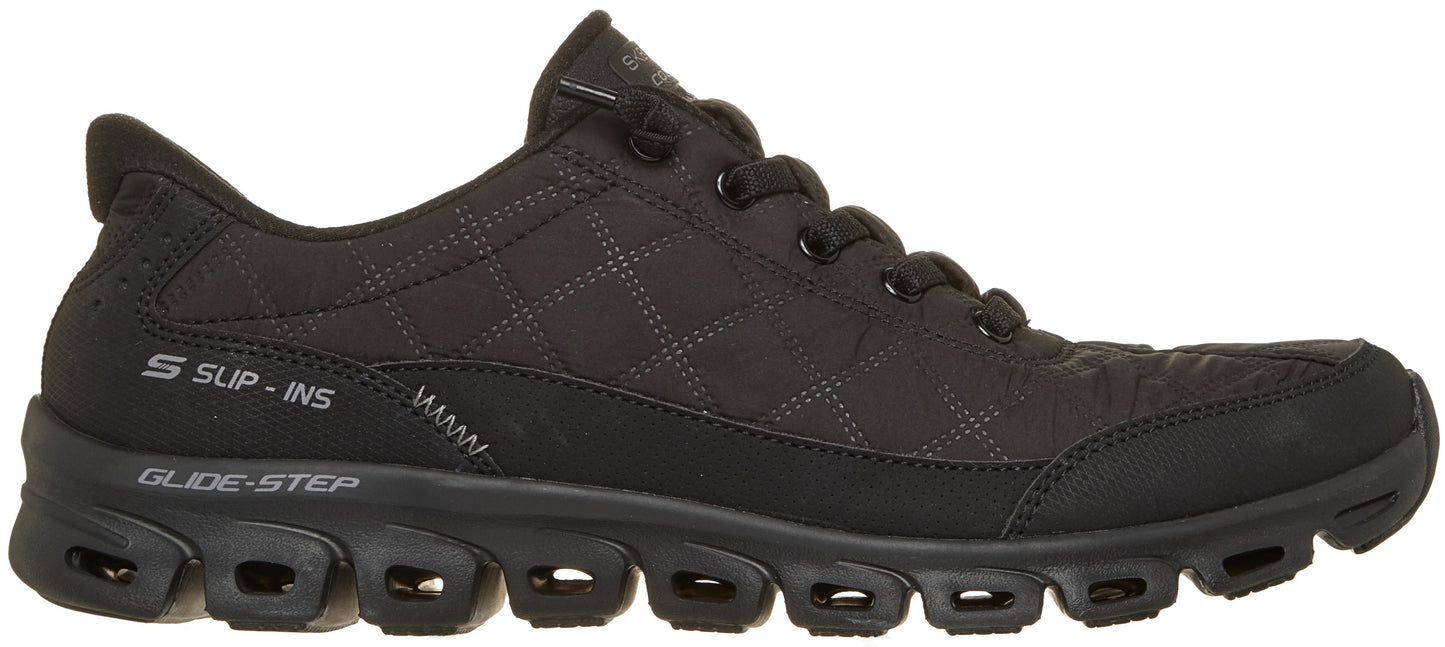 A black Skechers Slip-Ins Glide-Step athletic shoe, viewed from the side, with a quilted fabric upper, a thick lugged sole featuring visible cutouts, and laces on the upper.