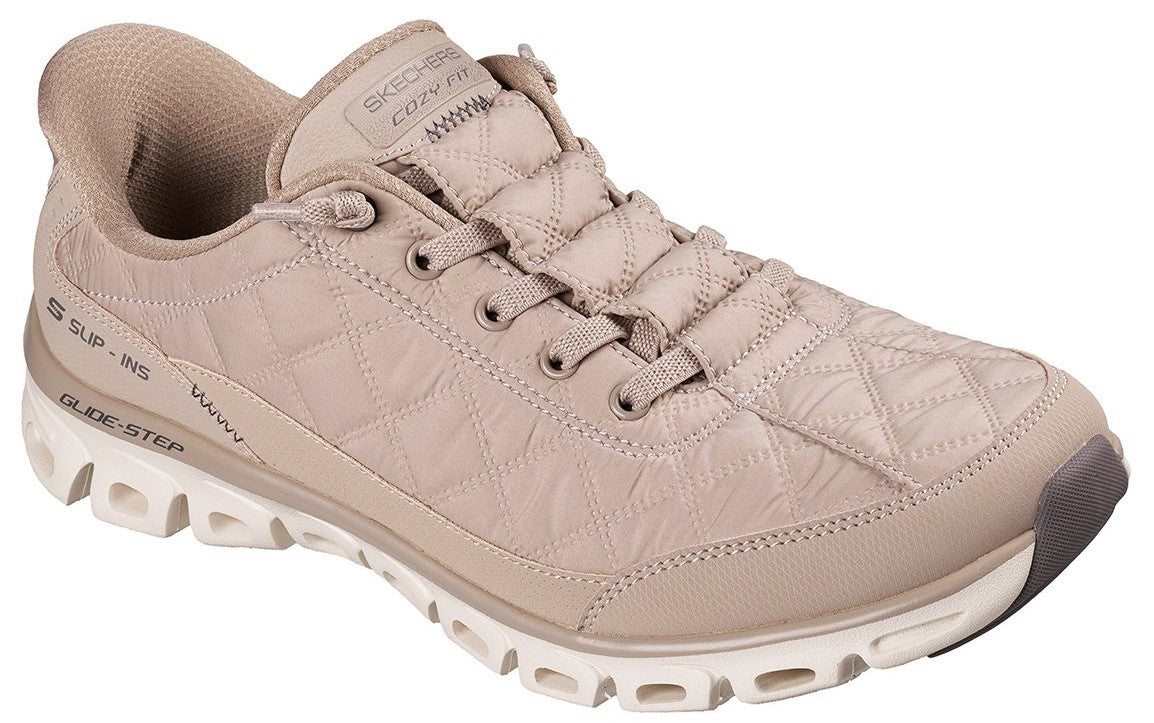 A beige, quilted-texture, low-top sneaker featuring a lace-up front, a padded collar, a thick, white, hollow-out patterned sole, and the visible text "SKECHERS COZY FIT" on the tongue and "SUP-INS GLIDE-STEP" on the heel.