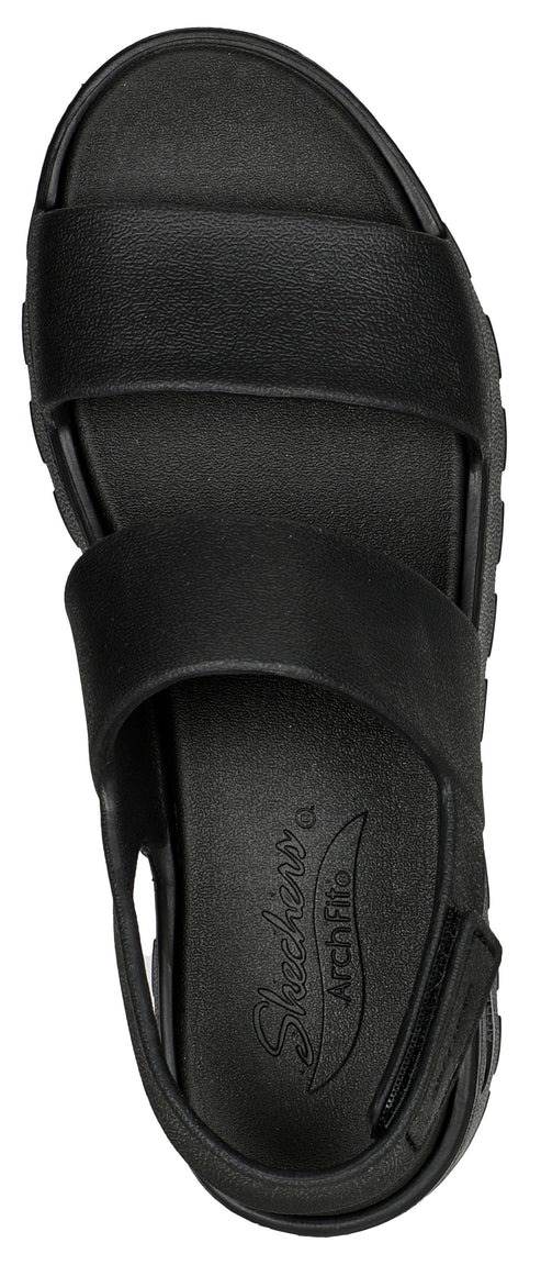 A black sandal with two straps and an open heel with text "Skechers Arch Fit" visible on the insole.