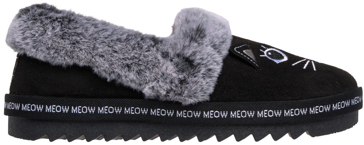 A black slip-on slipper featuring a plush grey faux-fur trim along the opening, a cat-themed design on the toe with an eye and whiskers, and a black sole rimmed with repeating white text that reads MEOW.