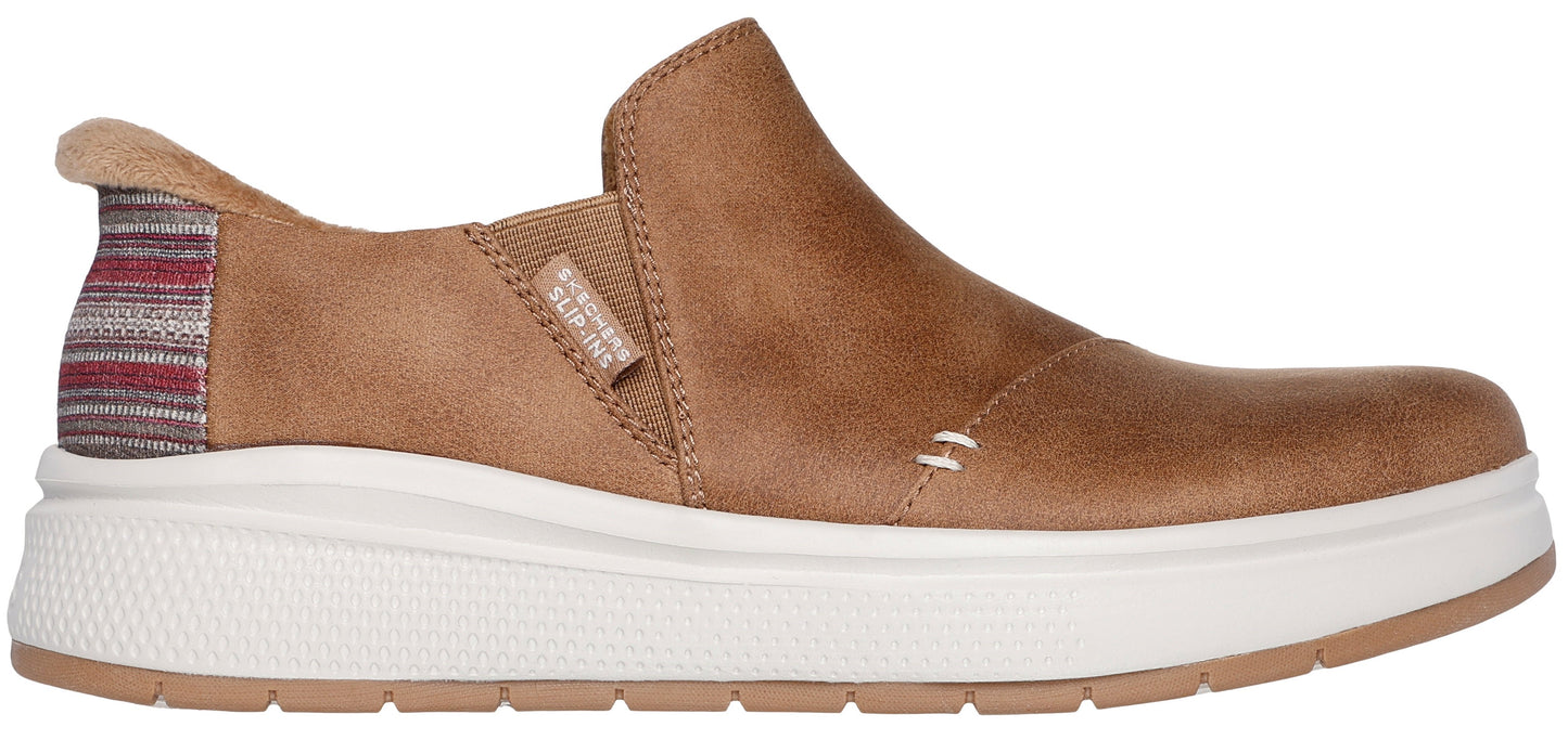 A tan slip-on shoe with a thick white sole and a colorful striped heel.