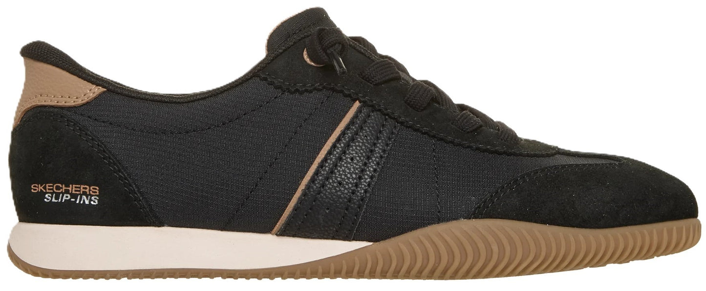A black Skechers Slip-ins sneaker with a tan heel accent, white midsole, and gum rubber textured outsole, showing a lateral view with the visible branding text Skechers Slip-ins.