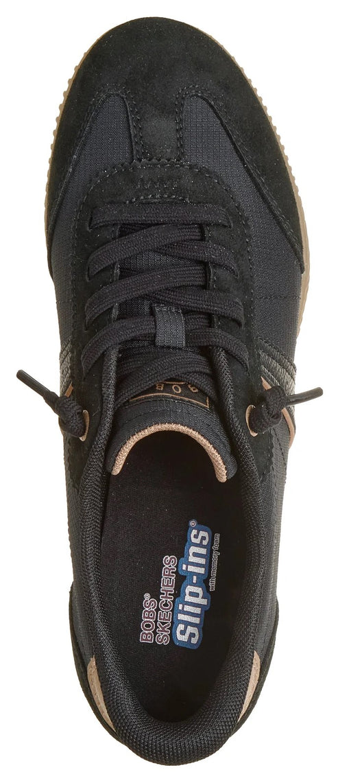 A top-down view of a black slip-in sneaker with tan accents on the tongue and heel, featuring laces and interior branding that reads BOBS SKECHERS Slip-ins.