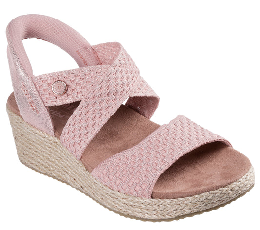 Pink wedge sandal with woven straps and elastic heel strap.