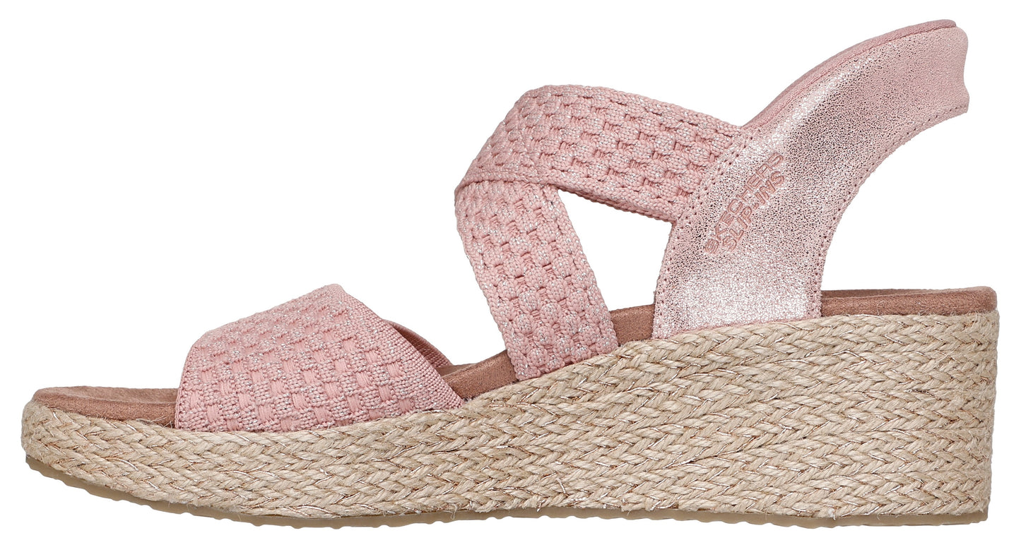 A pink sandal with woven cross straps and an espadrille wedge heel.