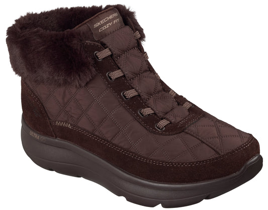 A brown women's ankle boot with a quilted upper, a faux-fur collar, and a thick, matching brown rubber sole with Skechers Cozy Fit branding on the tongue.