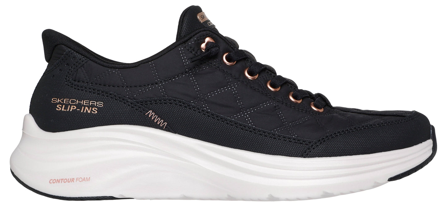 A black sneaker with rose gold details on the laces and logo that says "SKECHERS SLIP-INS".