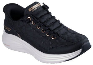 Low-top slip-on black shoe with white sole, rose-gold eyelets, and “COZY FIT” text on the tongue.
