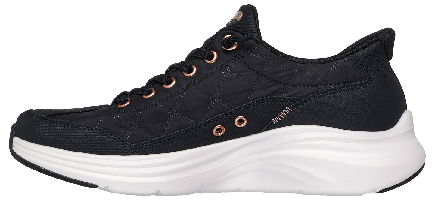 A black sneaker with rose gold accents and a thick white sole.