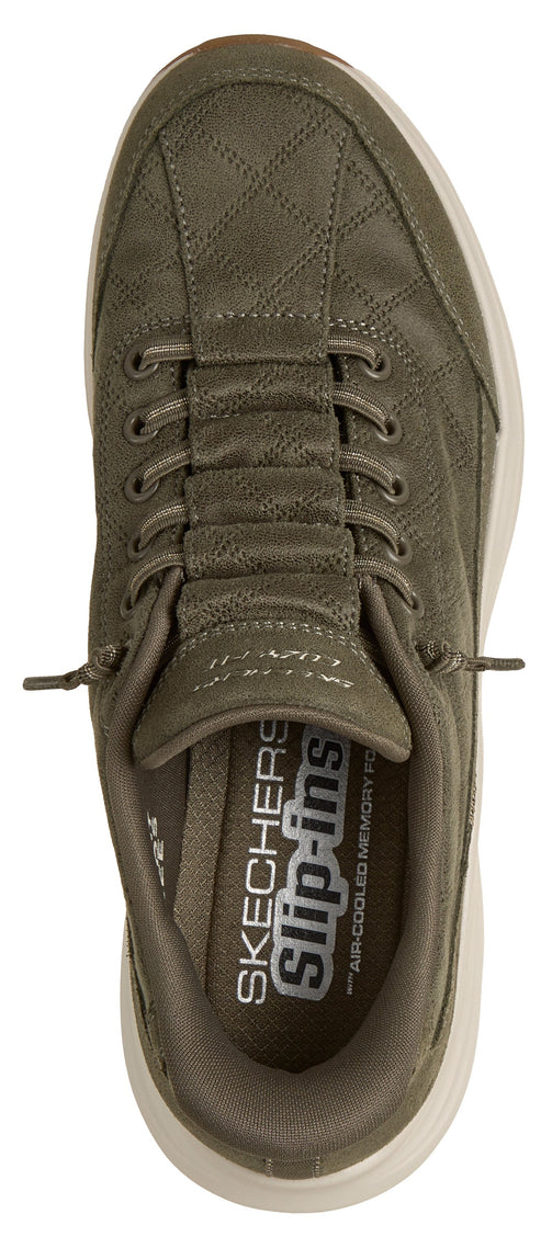An olive green slip-in sneaker shown from a top-down view, featuring a quilted patterned upper with decorative elastic laces and a white sole, with the interior footbed clearly labeled "SKECHERS slip-ins" and "AIR-COOLED MEMORY FOAM."