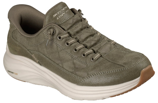 An olive green, quilted-fabric sneaker with a thick, white, textured midsole, lace-up front, and a tan rubber outsole, featuring 'SKECHERS COZY FIT' branding on the tongue and 'CONTOUR FOAM' text on the heel.