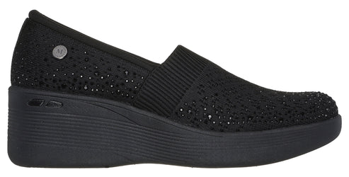 Black wedge slip-on shoe with elastic panel and metallic dots.