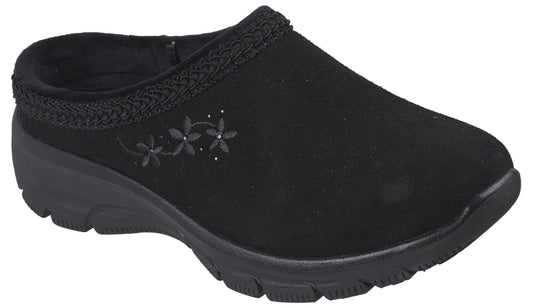 A black slip-on mule shoe made of a suede-like material, featuring a braided trim along the collar and an embroidered design of three small flowers with tiny dots on the outer side, set on a thick black molded rubber sole.