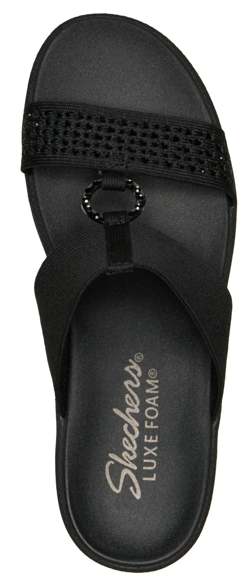 A black sandal with a jeweled strap and the text "Skechers LUXE FOAM" printed on the sole.