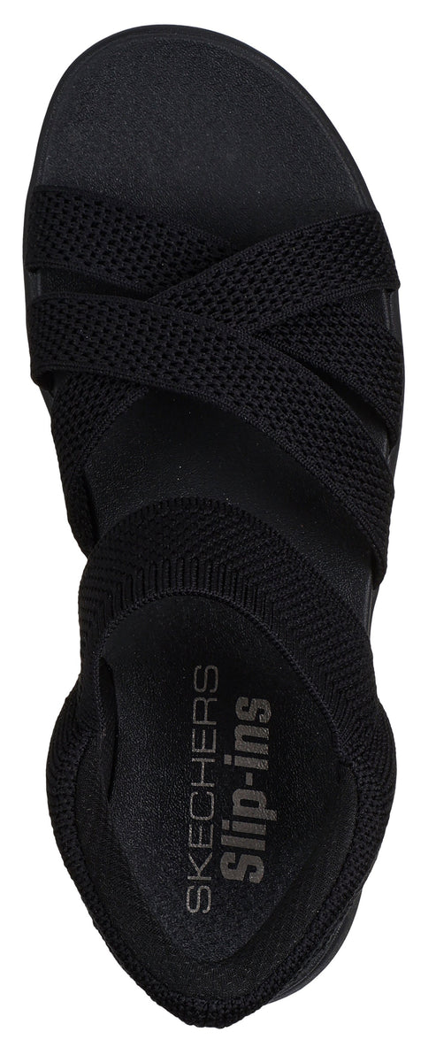 A black sandal with crisscross straps and the text "SKECHERS Slip-ins".