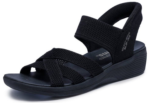 Black sandal with crisscross straps and wedge heel, featuring elastic straps and the text "SLIP-INS" on the heel strap.