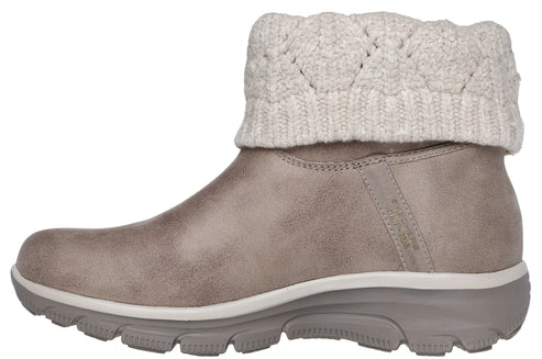 A tan slip-on ankle boot with a textured, cable-knit sweater cuff and a thick, ridged grey outsole.