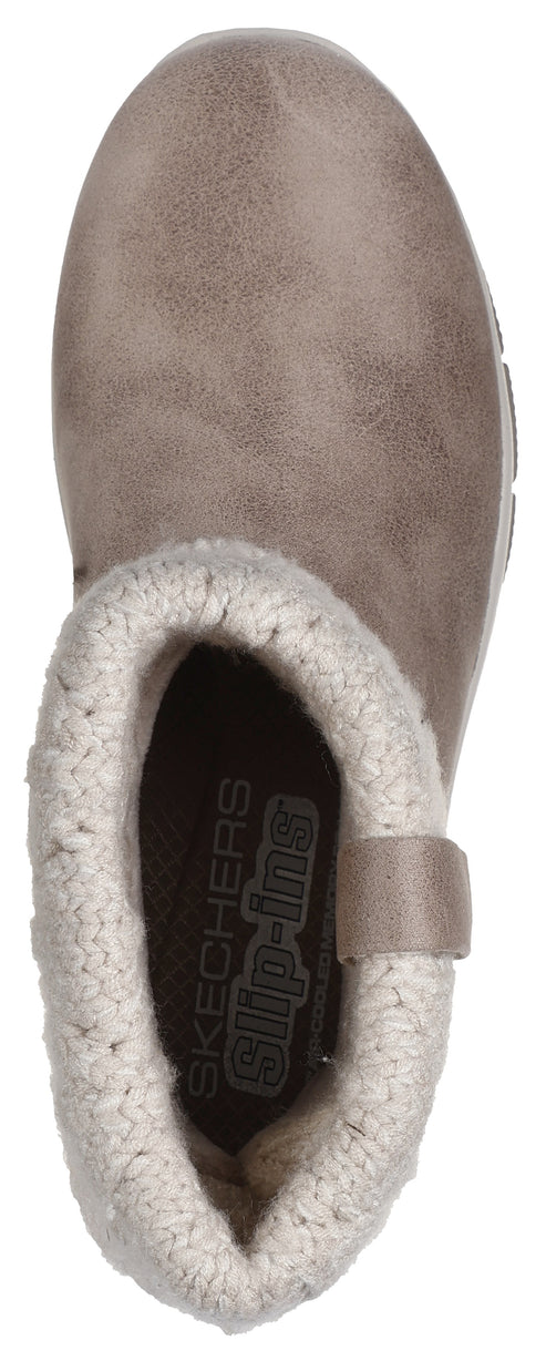 A top-down view of a light brown, slip-on ankle boot with a fuzzy, white, sweater-knit cuff, displaying the text 'SKECHERS Slip-ins' inside the heel.
