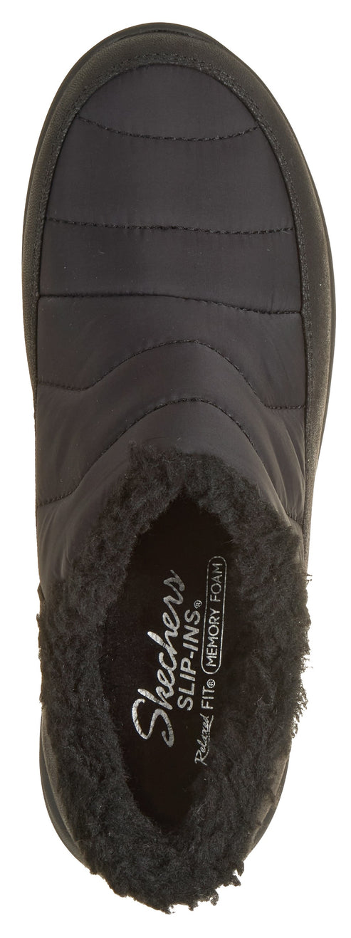 A top-down view of a black, slip-on, quilted ankle boot featuring a fluffy black faux fur collar and an interior insole printed with 'Skechers Slip-ins Relaxed Fit Memory Foam'.