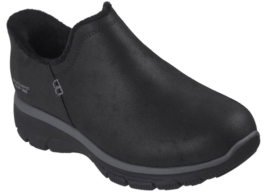 A black, slip-on sneaker featuring a solid, smooth upper, a warm, fuzzy-lined collar, and a thick, dark gray and black textured sole, with the words 'Skechers Slip-ins' visible on the side.