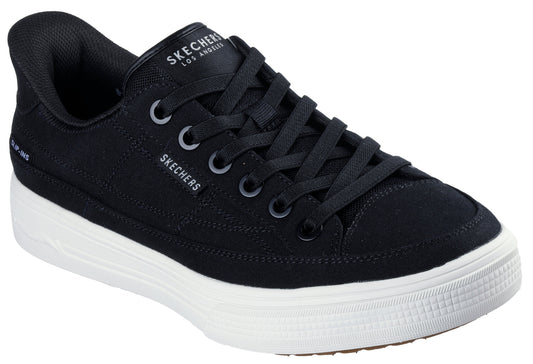 A black canvas sneaker with black laces and a thick white sole. "SKECHERS LOS ANGELES" is printed on the tongue. "SKECHERS" is printed on the side.