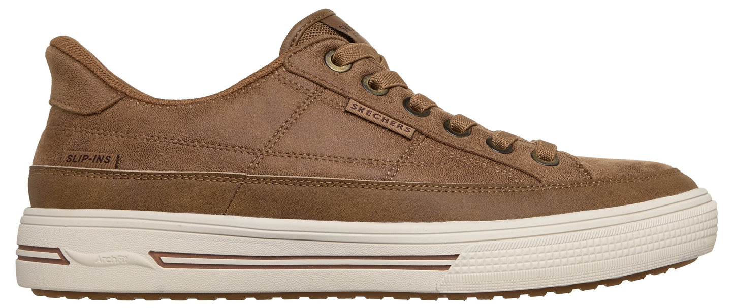 A brown leather low-top sneaker featuring a thick white rubber sole, a lace-up front with a metal logo tag on the side, and a 'SLIP-INS' label near the heel.