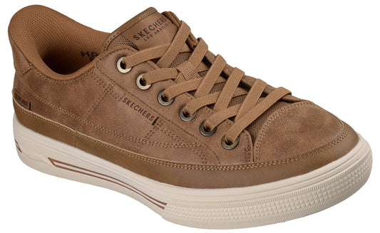 A brown suede lace-up sneaker with a chunky, textured off-white rubber sole, featuring visible stitching, metallic eyelets, and Skechers branding on the tongue and side.