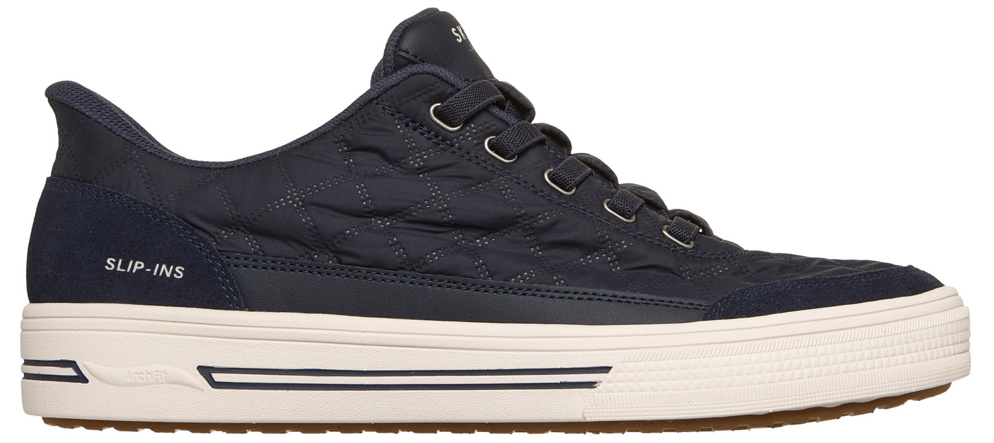 A dark navy blue sneaker with a quilted fabric upper, a thick white rubber sole with black stripe details, and the words "SLIP-INS" printed on the heel area.