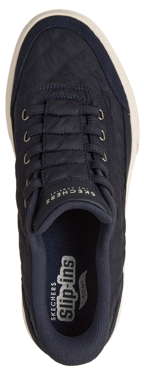 A top-down view of a dark blue, quilted, slip-on sneaker featuring a Skechers Slip-ins logo on the insole and branding on the tongue.