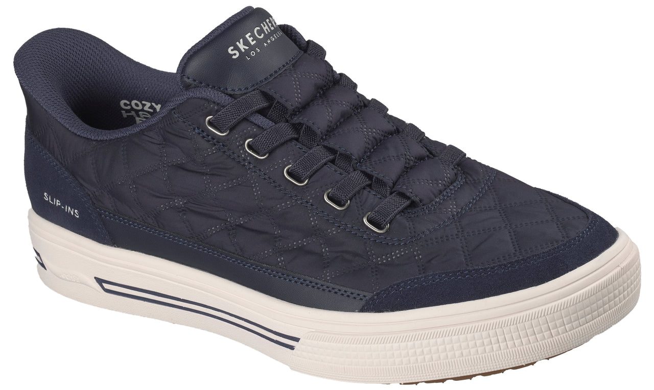 A navy blue, quilted slip-on sneaker featuring a thick white rubber sole with dark blue accents, a padded collar, and the text "SKECHERS LOS ANGELES" on the tongue and "SLIP-INS" on the side.