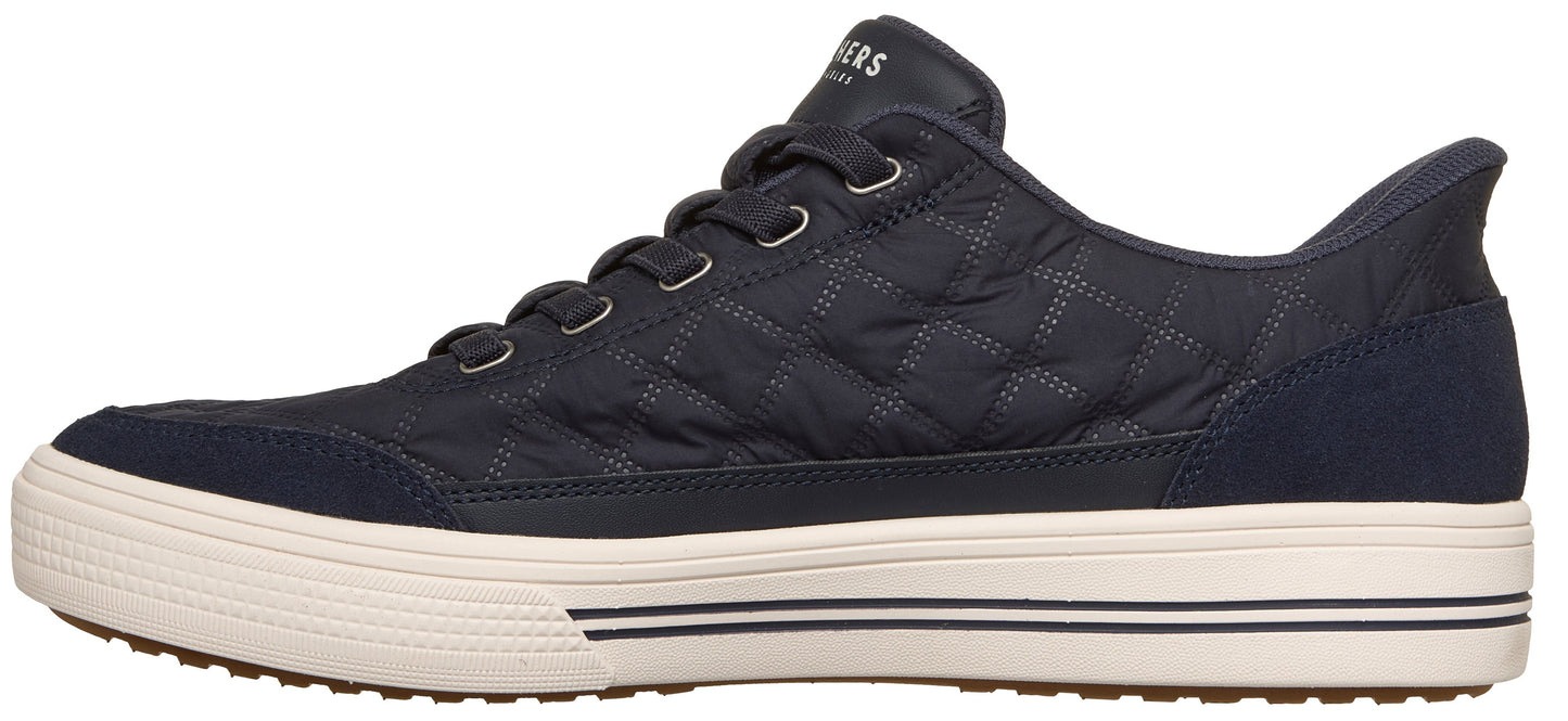 Side view of a dark navy quilted sneaker with a thick cream-colored textured rubber sole with black stripes, featuring blue suede overlays at the toe and heel.