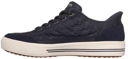 Side view of a dark navy quilted sneaker with a thick cream-colored textured rubber sole with black stripes, featuring blue suede overlays at the toe and heel.