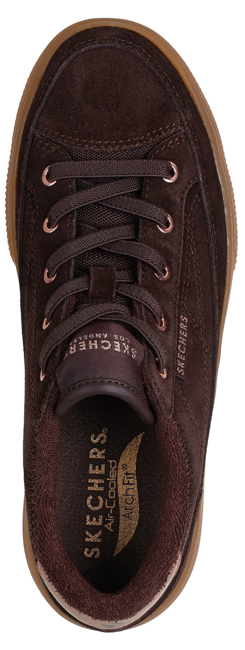 A top-down view of a dark brown suede lace-up sneaker with a light brown rubber sole, featuring SKECHERS Los Angeles branding on the tongue and SKECHERS Air-Cooled Arch Fit branding on the insole.