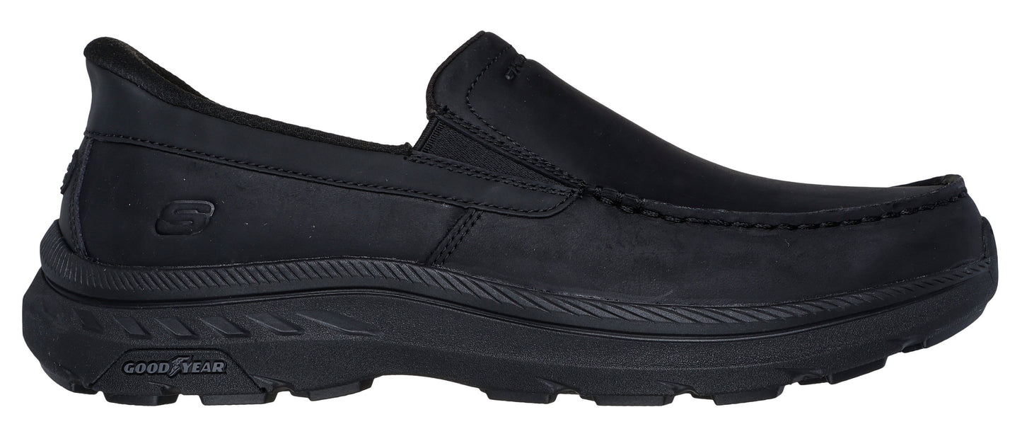 Black slip-on moccasin shoe with a thick, textured sole featuring a Goodyear logo.