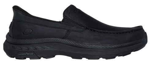 Black slip-on moccasin shoe with a thick, textured sole featuring a Goodyear logo.