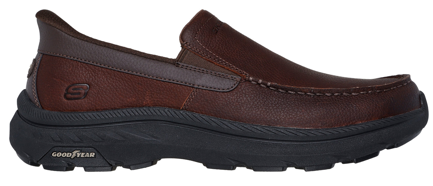 A brown slip-on shoe with black sole.