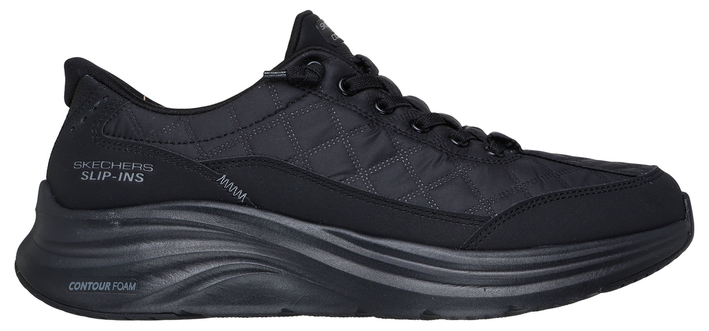 A black sneaker with laces and a thick sole. "SKECHERS SLIP-INS" and "CONTOUR FOAM" are printed on the side of the shoe.