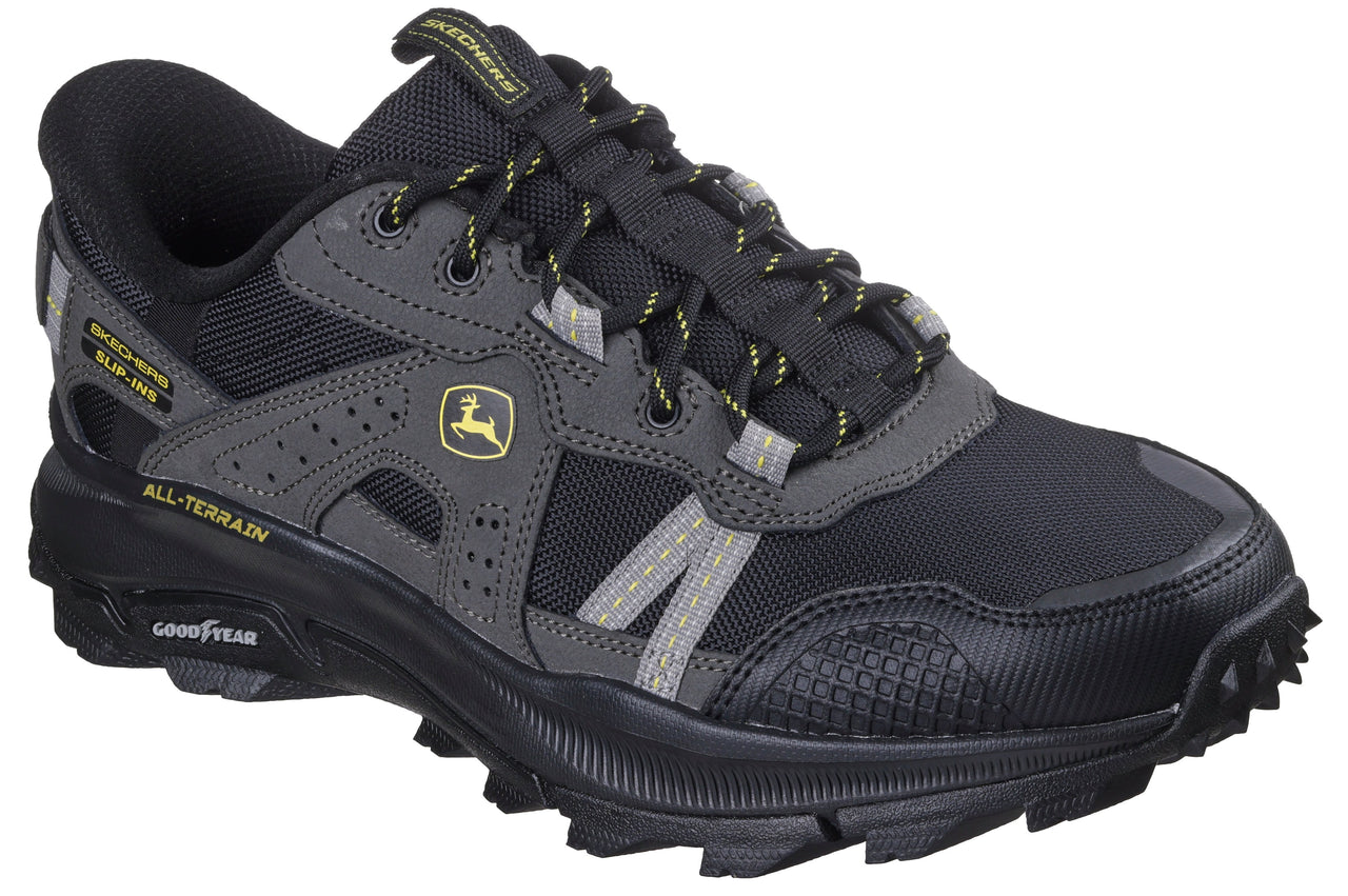 A black and gray athletic shoe with Goodyear sole and All-Terrain text; green and yellow John Deere logo visible on side.