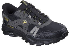 A black and gray athletic shoe with Goodyear sole and All-Terrain text; green and yellow John Deere logo visible on side.
