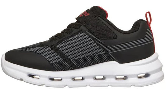 Side view of a black sneaker with a white midsole that has hollow oval-shaped openings. The shoe has black laces and a black strap over the top of the foot. The tongue is red with the word 