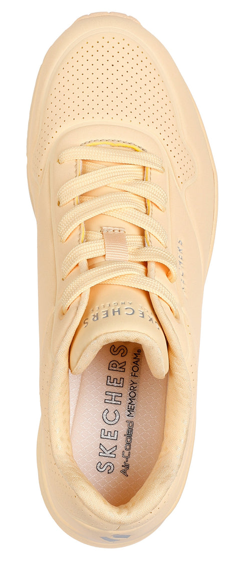 Top-down view of a yellow sneaker with laces and a perforated toe.
