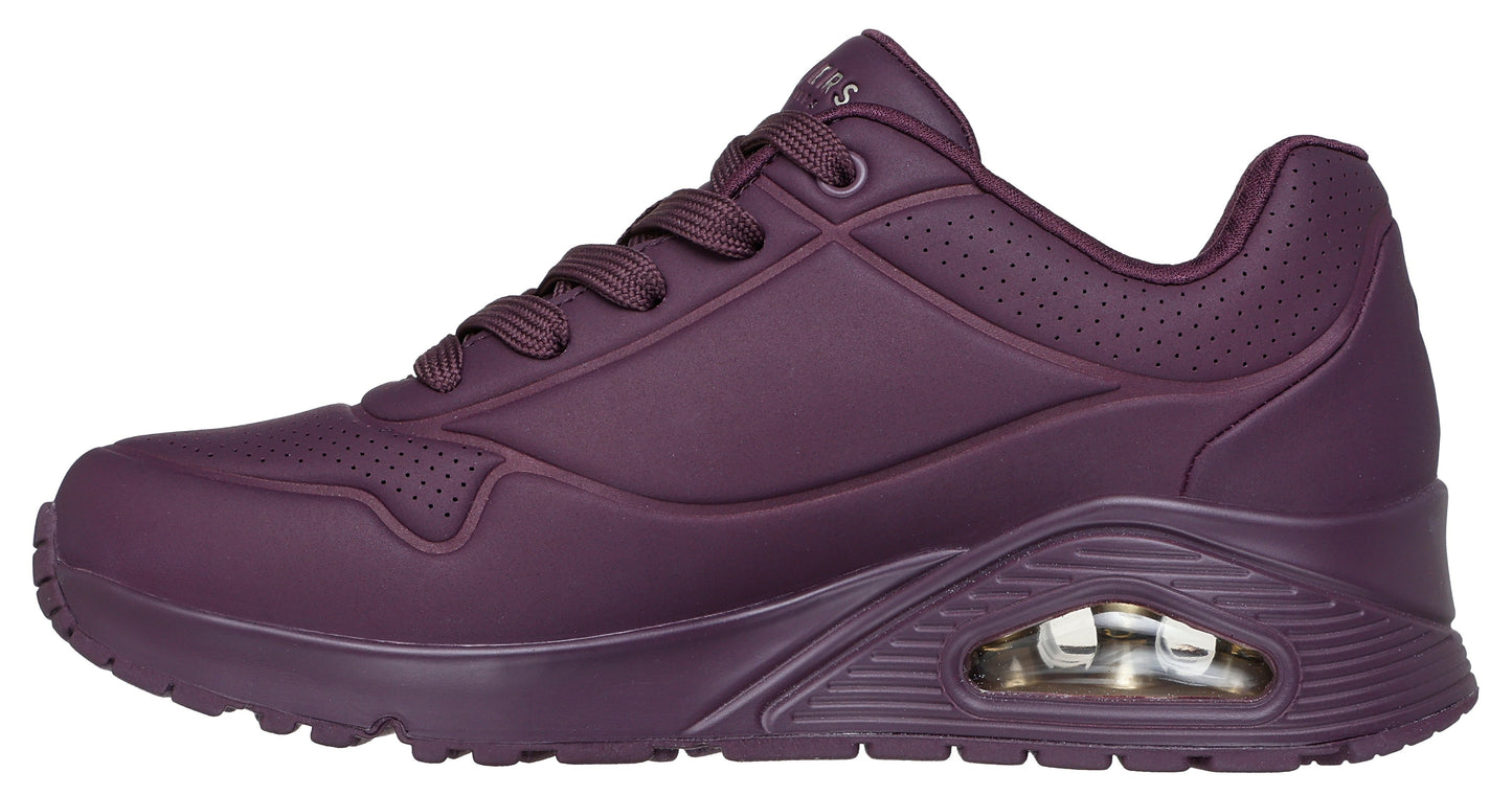 Side view of a matte dark purple sneaker featuring a lace-up closure, raised textured sole, and breathable perforated accents.