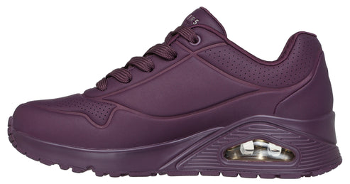 Side view of a matte dark purple sneaker featuring a lace-up closure, raised textured sole, and breathable perforated accents.