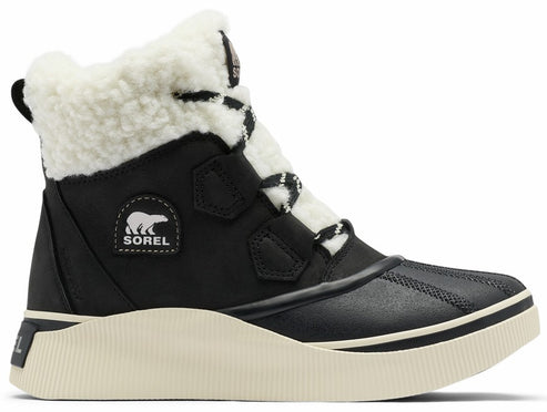 A black Sorel ankle boot with a white fuzzy fleece collar, a white textured platform rubber sole, and a black lace-up front with a Sorel bear logo patch on the side.