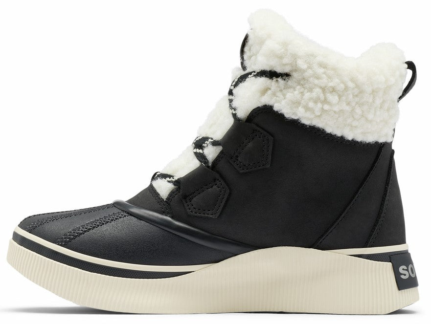 A black winter boot with a white faux-shearling cuff, a thick off-white rubber sole, and a rubberized toe cap, featuring black laces with white detailing and a small 'SO' logo on the heel.
