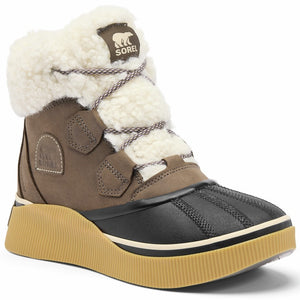 A brown and black winter boot featuring a white faux-shearling cuff and tongue, lace-up closure, a black rubberized toe cap, and a textured tan platform sole, with a Sorel brand patch on the tongue.