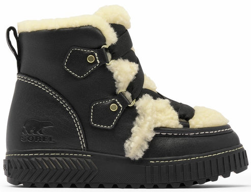 A black leather ankle boot with cream-colored faux shearling trim, brass-toned hardware, white stitching, and a chunky, textured black rubber sole.