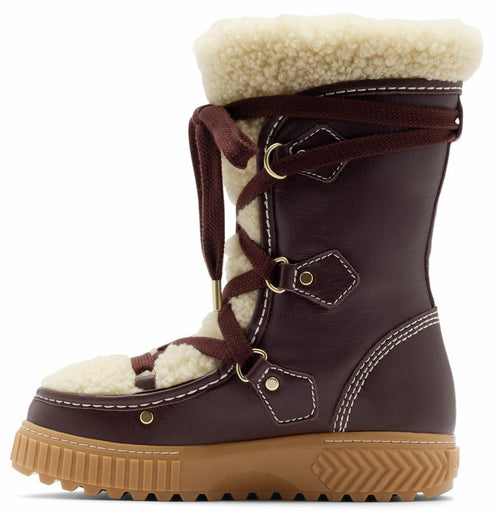 A brown, mid-calf winter boot with a cream-colored, fuzzy shearling lining and trim at the top and front, featuring dark brown lace-up closure with gold-tone hardware, white contrast stitching throughout, and a thick, ridged, light brown rubber lug sole.
